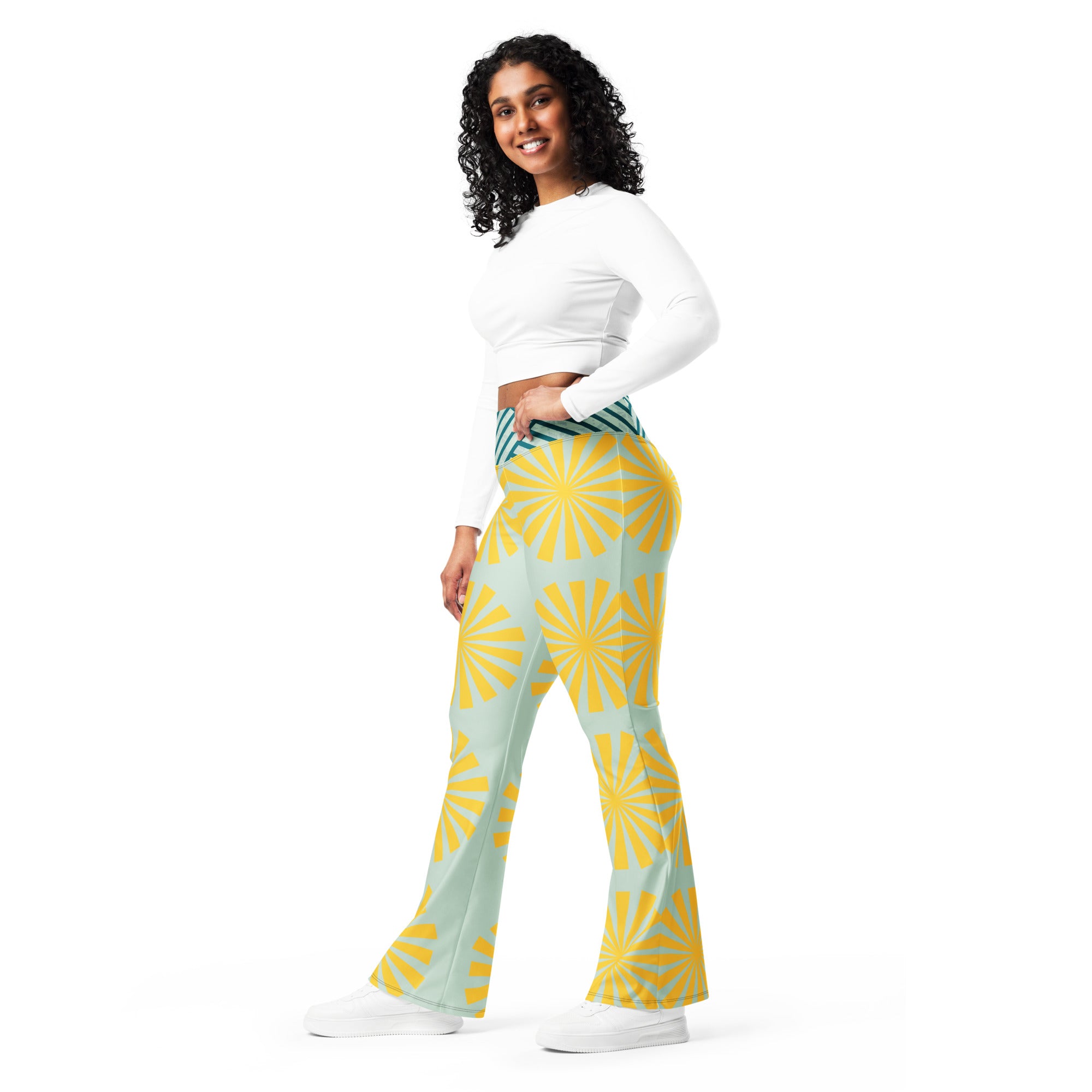 Legging évasé bleu clair à motif soleil jaune, porté de côté, taille rayée vert foncé.