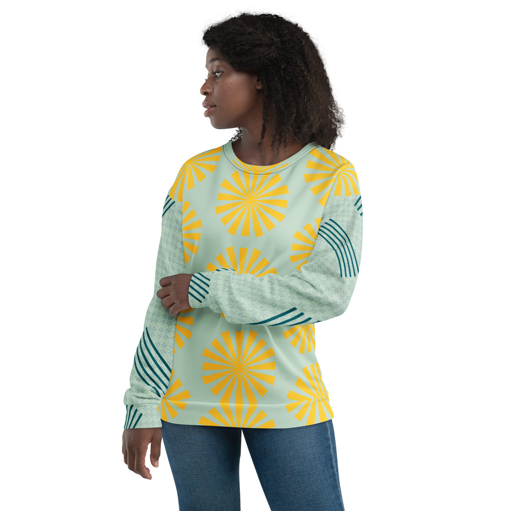 Sweat-shirt bleu clair à motifs fleurs jaunes, porté de profil, manches longues avec empiècement rayé.