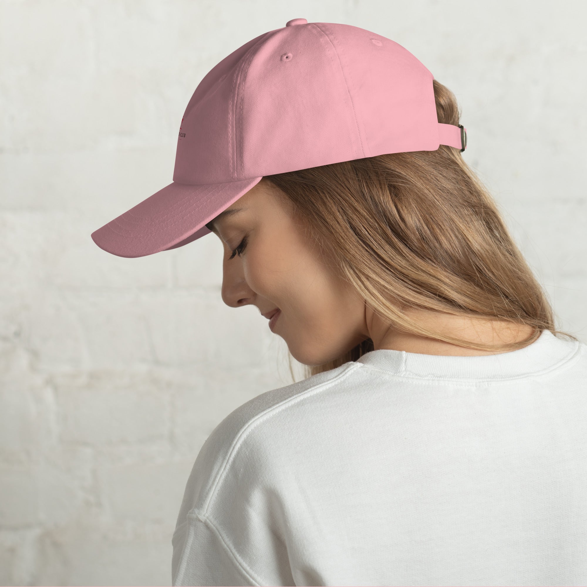 Casquette rose portée de côté, visière courbée et sangle réglable au niveau de la nuque.
