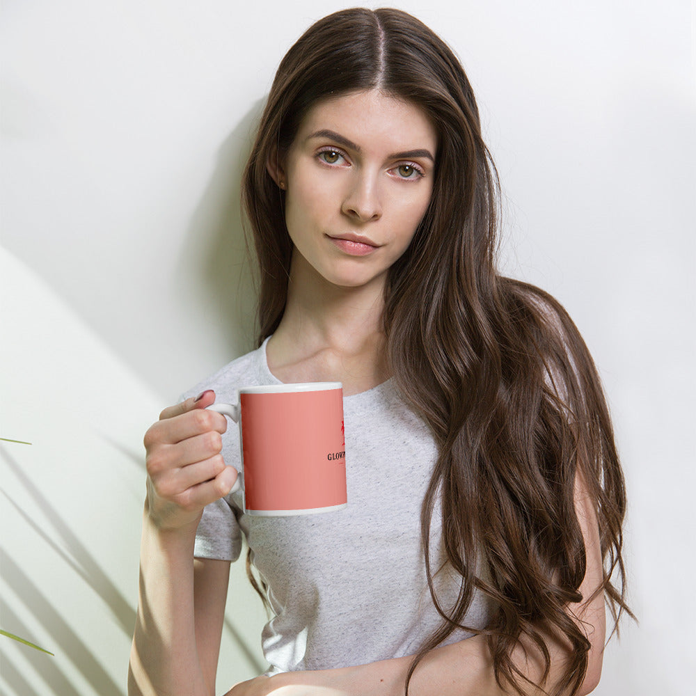 Mug rose brillant avec intérieur blanc et logo Glowfit-Club, tenu à la main.