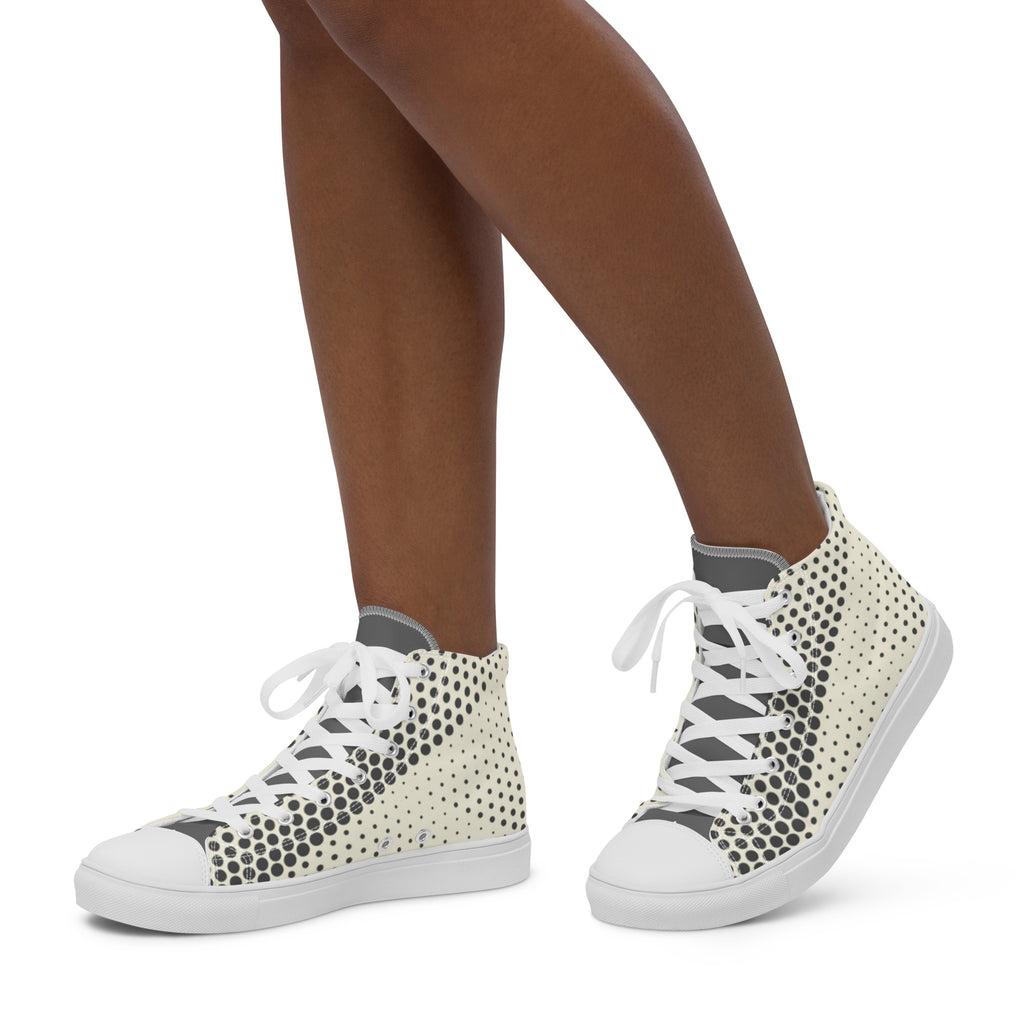 Personne portant des baskets hautes en toile crème à pois noirs, lacets blancs.